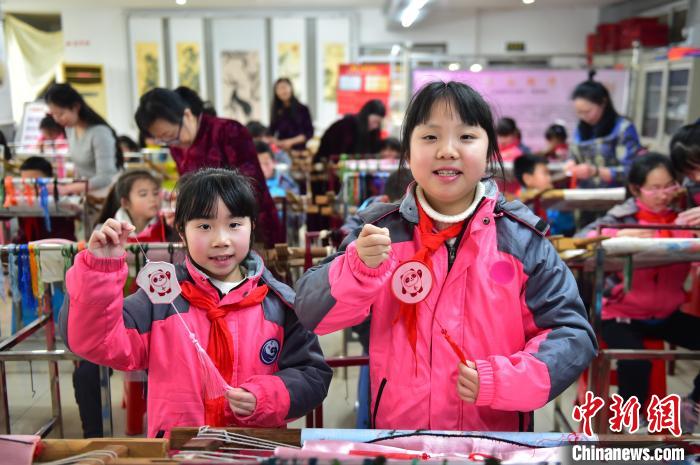 圖為小學(xué)生展示繡制好的2022年北京冬奧會(huì)吉祥物“冰墩墩”形象?！∮髟屏?攝