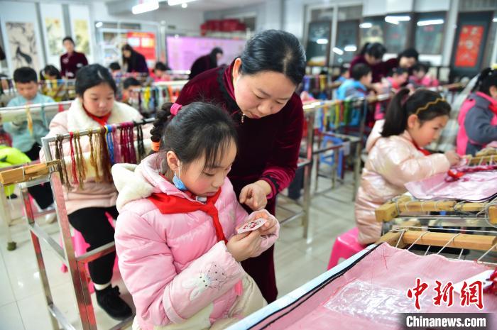 江西省級(jí)非遺豫章繡傳承人手把手指導(dǎo)小學(xué)生繡制2022年北京冬奧會(huì)吉祥物“冰墩墩”形象。　喻云亮 攝