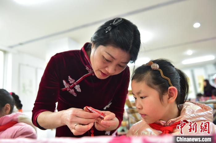 江西省級(jí)非遺豫章繡傳承人手把手指導(dǎo)小學(xué)生繡制2022年北京冬奧會(huì)吉祥物“冰墩墩”形象。　喻云亮 攝