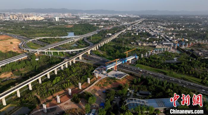 航拍正在建設(shè)的跨越成都繞城高速公路連續(xù)梁施工現(xiàn)場，旁邊依次為已運(yùn)營的成渝高速鐵路和機(jī)場高速公路?！⒅铱?攝