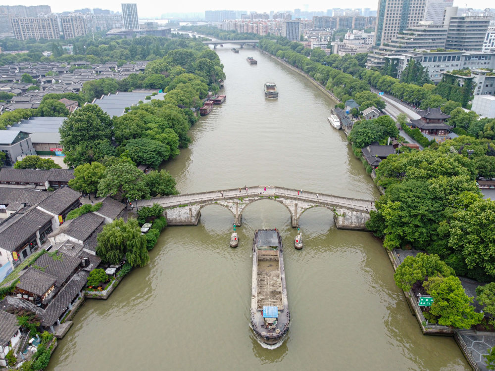 5月27日，一艘貨船駛過京杭大運河南端標(biāo)志建筑杭州拱宸橋。(無人機照片)新華社記者江漢 攝