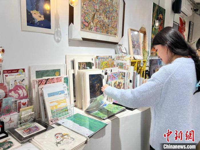圖為藝術(shù)品商店內(nèi)，顧客挑選插畫作品?！＄婌?攝