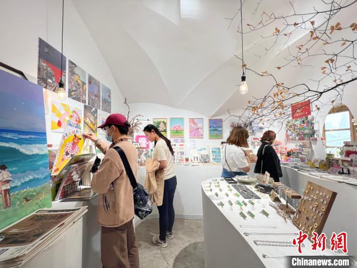 圖為藝術(shù)品商店內(nèi)，顧客挑選插畫作品?！＄婌?攝