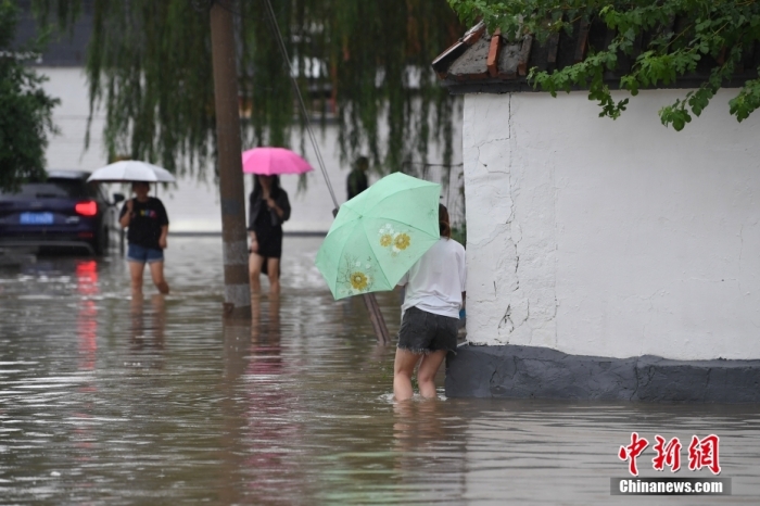 7月31日，市民行走在雨中的北京房山區(qū)瓦窯頭村。北京市氣象臺(tái)當(dāng)日10時(shí)發(fā)布分區(qū)域暴雨紅色預(yù)警信號(hào)。北京市水文總站發(fā)布洪水紅色預(yù)警，預(yù)計(jì)當(dāng)日12時(shí)至14時(shí)，房山區(qū)大石河流域?qū)⒊霈F(xiàn)紅色預(yù)警標(biāo)準(zhǔn)洪水。<a target='_blank' href='/'><p  align=
