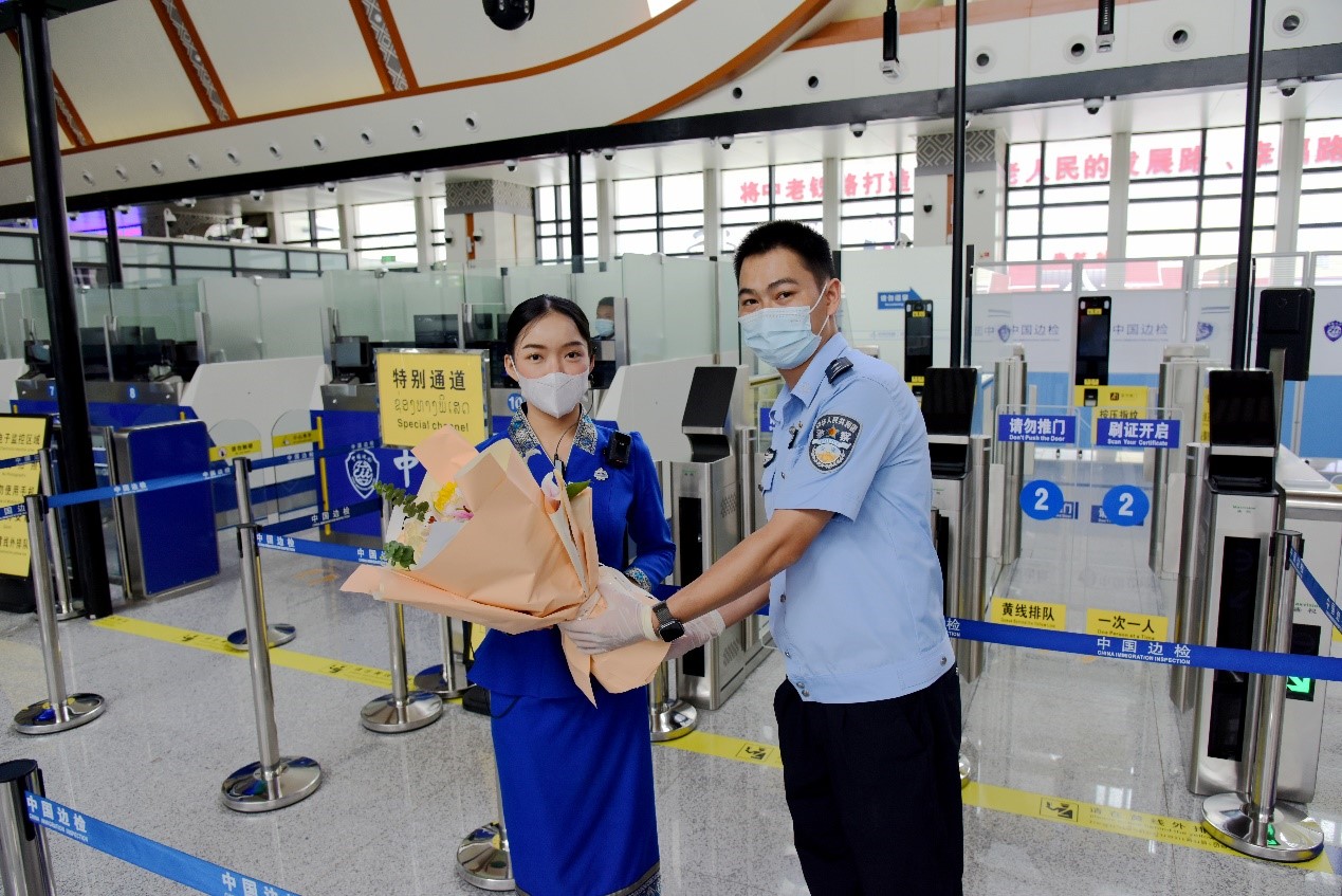 磨憨出入境邊防檢查站民警為中老鐵路第100萬名出入境旅客，D888次國際旅客列車老撾籍乘務(wù)員森達拉·妮緹婭（Sengdala Nitiya），送上鮮花。黃遠飛 攝