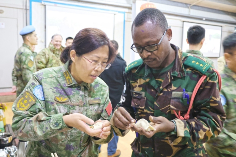 圖為維和官兵與外軍人員共同包餃子。胡光明攝