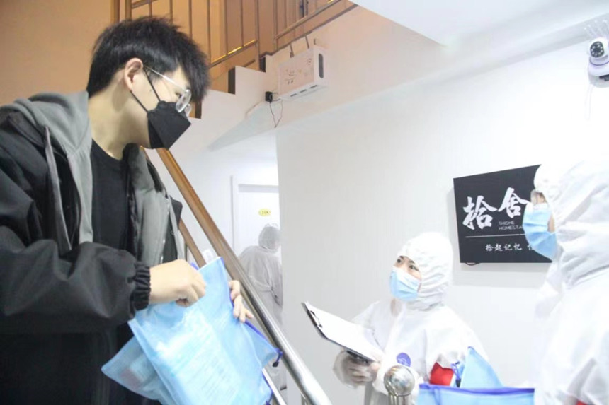 社區(qū)工作人員和志愿者身穿防護(hù)服上門送馬應(yīng)龍大健康防疫包。徐帥攝