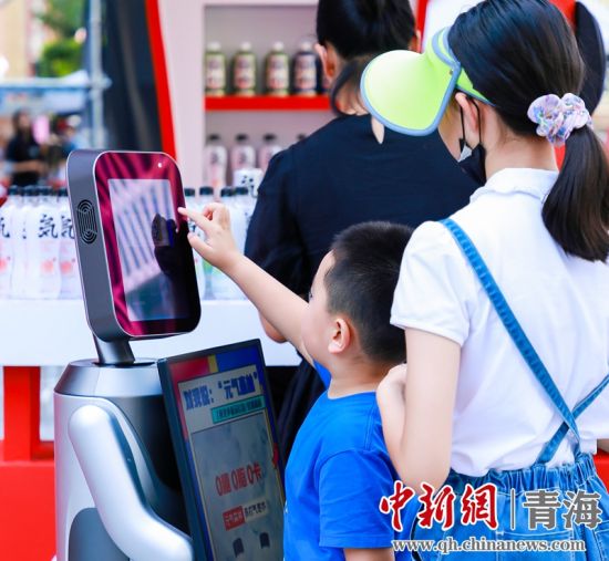 圖為一名小朋友正在和機(jī)器人“志愿者”進(jìn)行互動(dòng)。 沐聞 攝
