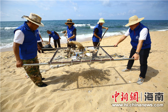 環(huán)保志愿者用篩網“淘”出海灘上的垃圾。