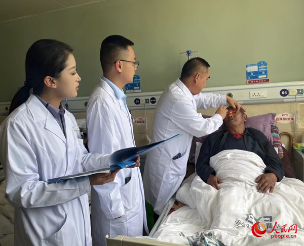董光明（左三）帶領(lǐng)醫(yī)生對患者進行術(shù)前檢查。人民網(wǎng)記者 杜燕飛攝