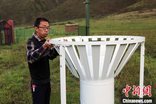 圖為班瑪縣氣象局工作人員在維護(hù)藏雪茶基地氣候站。青海省氣象局供圖