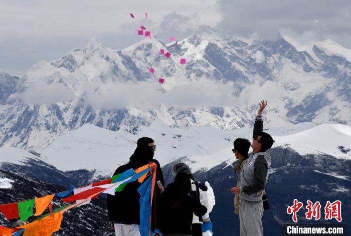 圖為5月14日，游客在西藏林芝色季拉山觀景臺拋灑“隆達”(風馬旗，藏族民眾的一種祈福方式)?！±盍?攝