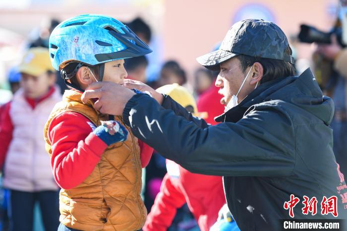 圖為拉薩市實(shí)驗(yàn)幼兒園孩子在教練的幫助下穿戴頭盔?！『闻罾?攝