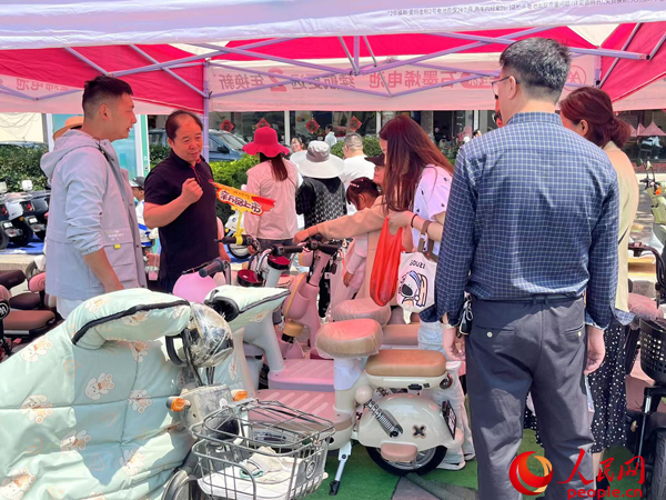 某電動自行車品牌工作人員向消費(fèi)者介紹以舊換新相關(guān)情況。人民網(wǎng)記者 杜燕飛攝