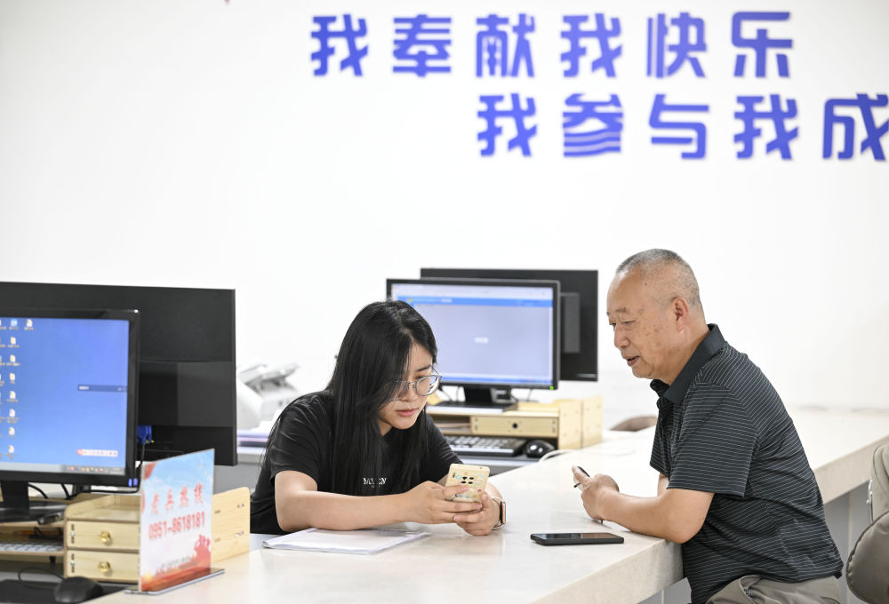 2024年6月20日，在寧夏銀川市金鳳區(qū)長城花園社區(qū)黨群服務(wù)中心，工作人員幫助居民辦理業(yè)務(wù)。圖片來源 新華社