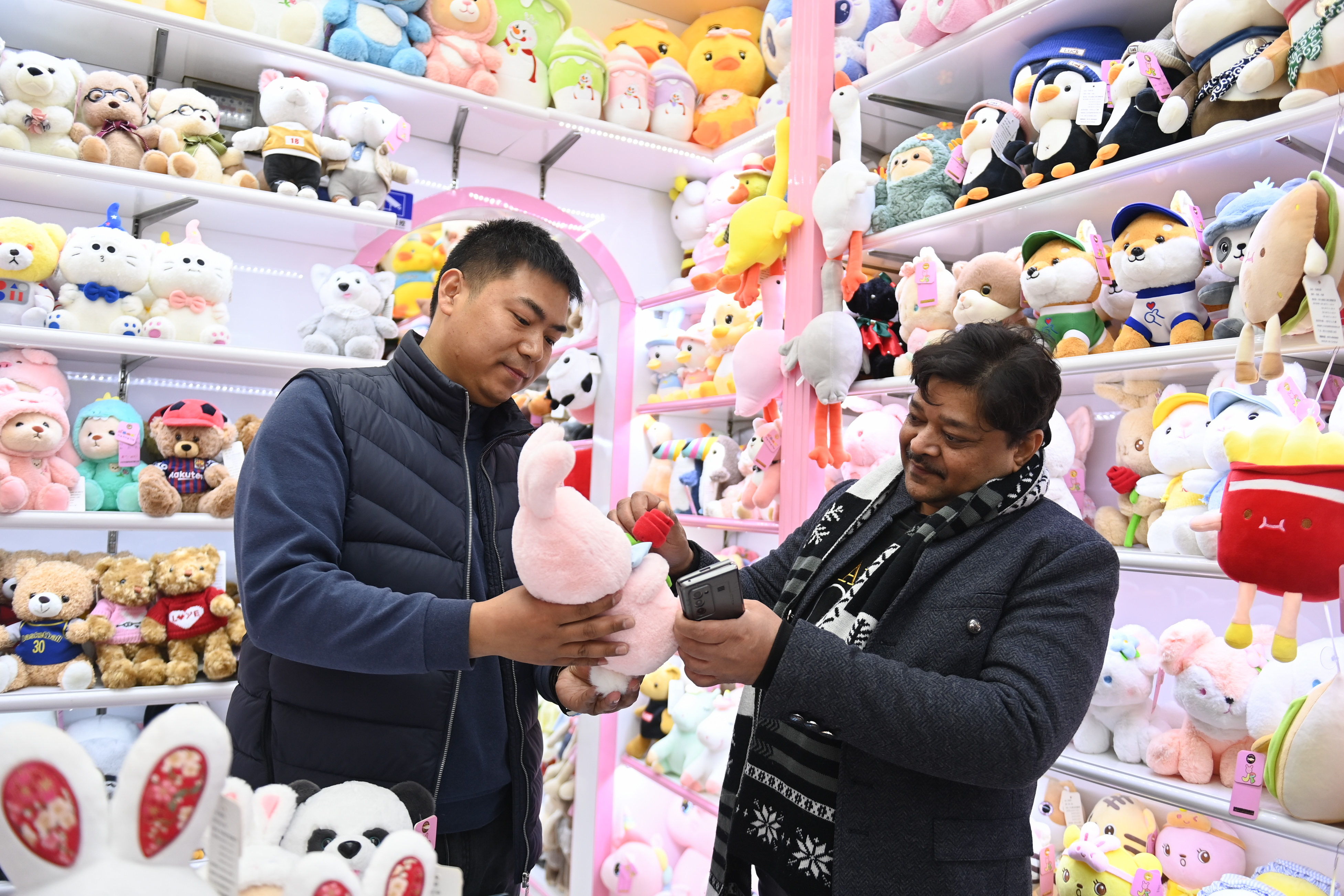 2023年2月2日，來自印度的客商（右）在義烏國(guó)際商貿(mào)城的一家玩具店鋪內(nèi)選購(gòu)。