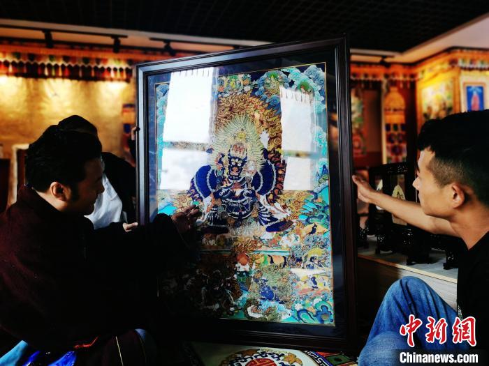 圖為久美尖措(左)與徒弟們展示唐卡作品?！?zhí)砀?攝