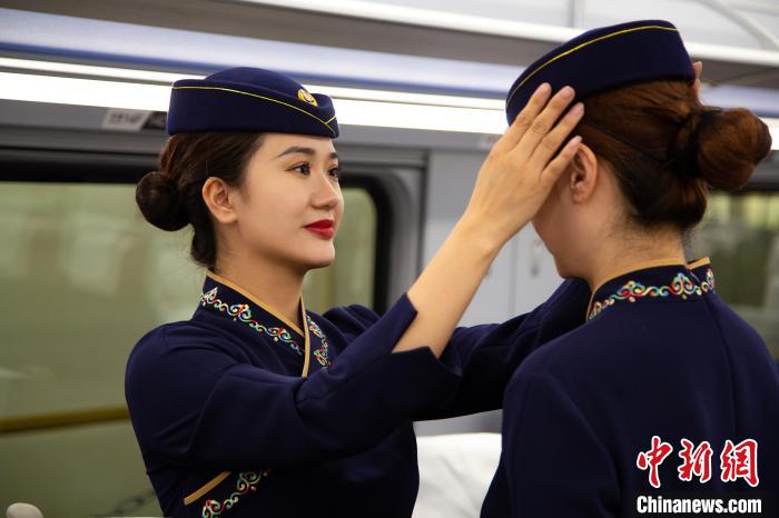 圖為青藏鐵路西格段“復(fù)興號”動車組乘務(wù)員互相整理新制服?！±罾?攝
