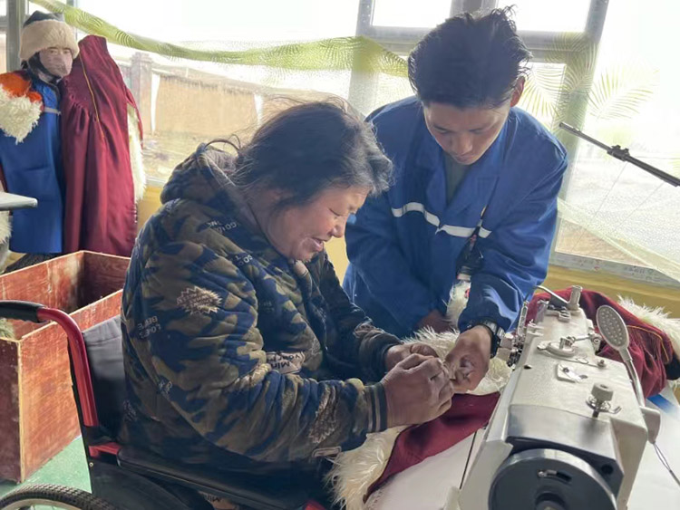 扎西奪爾登幫助殘疾員工裁剪。阿壩州文明辦供圖