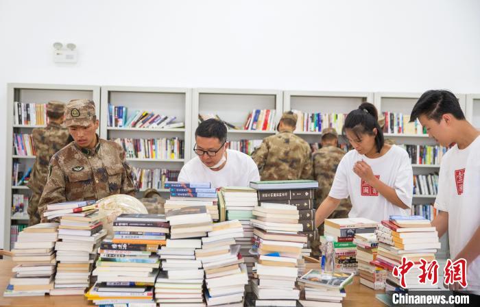 圖為志愿者們和邊防戰(zhàn)士整理圖書(shū)?！詵| 攝