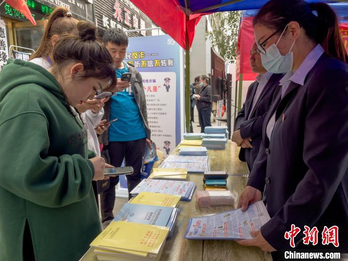圖為工作人員正在向路過(guò)市民介紹國(guó)家反詐中心軟件的功能?！≈x牧 攝