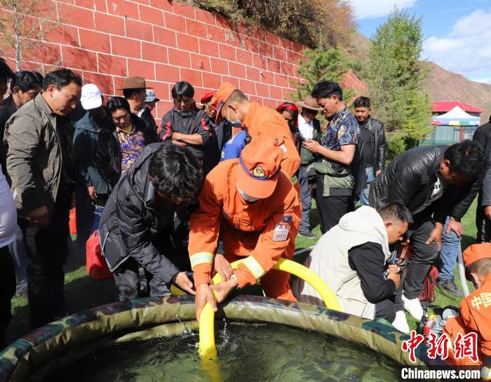 圖為森林消防員為護(hù)林員講解滅火裝備的使用方法?！〔际猩窒乐ш?duì) 供圖