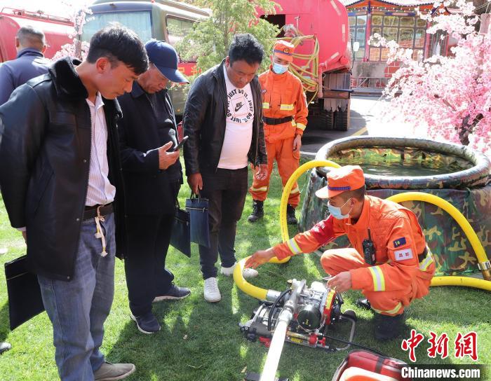圖為森林消防員為護(hù)林員講解滅火裝備的使用方法?！〔际猩窒乐ш?duì) 供圖