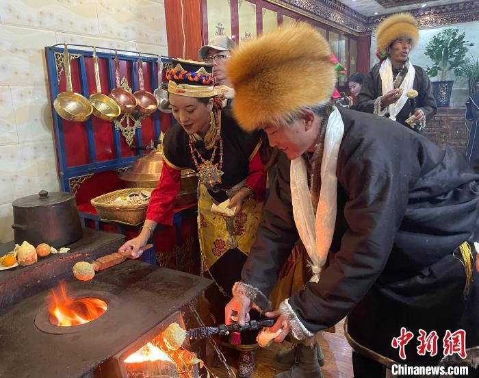 圖為人們在火上烤節(jié)日美食“結(jié)達”?！∪轿木?攝