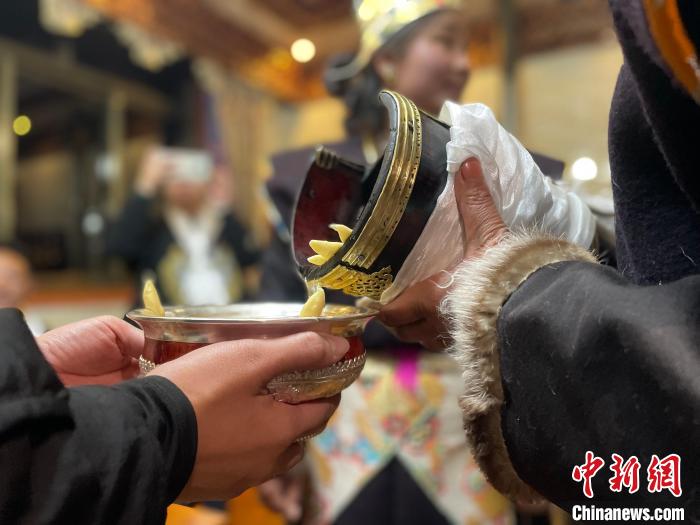 圖為主人在碗中斟滿青稞酒?！∪轿木?攝