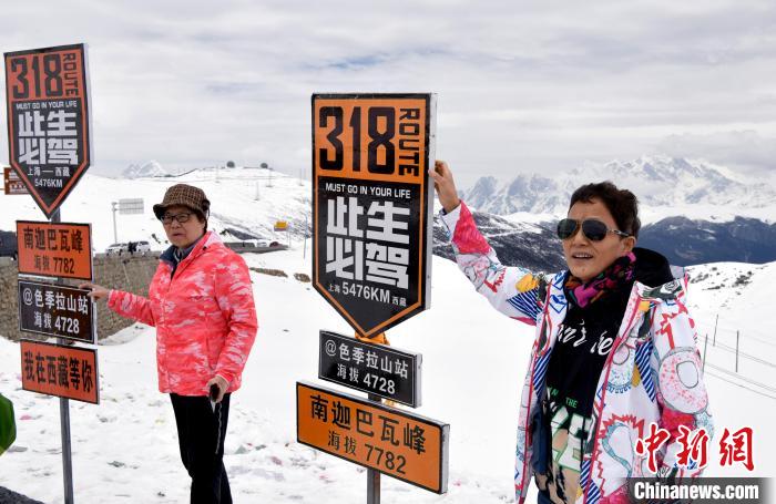 圖為5月14日，西藏林芝色季拉山觀景臺(tái)，游客與南迦巴瓦峰合影。　李林 攝